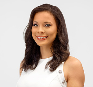 A woman smiling at the camera, she has medium length brown hair